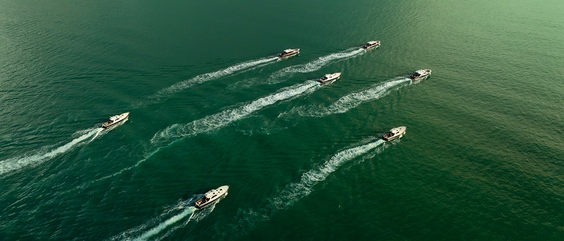 Small fleet of B&G yachts cruising in formation on the water.