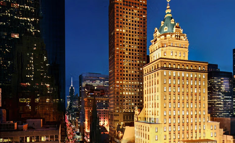 Exterior of Aman New York hotel with city lights and skyline at dusk