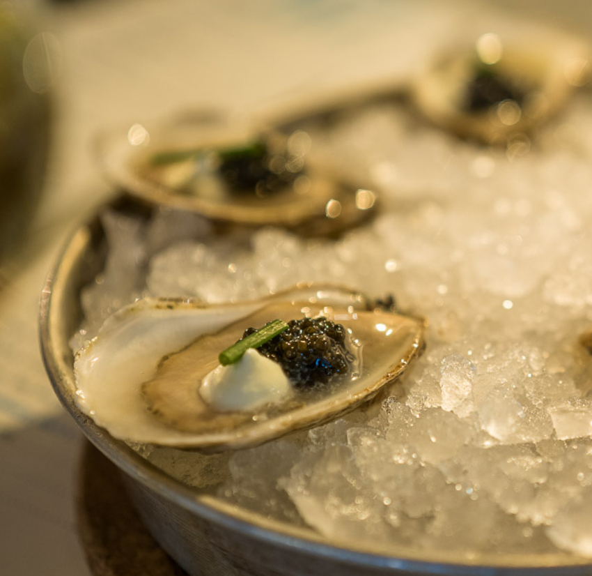 Beautiful raw oyster with caviar and creme fraiche on ice.