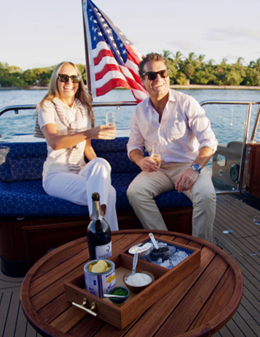 A couple enjoying drinks and caviar aboard a Barton & Gray Daychaser