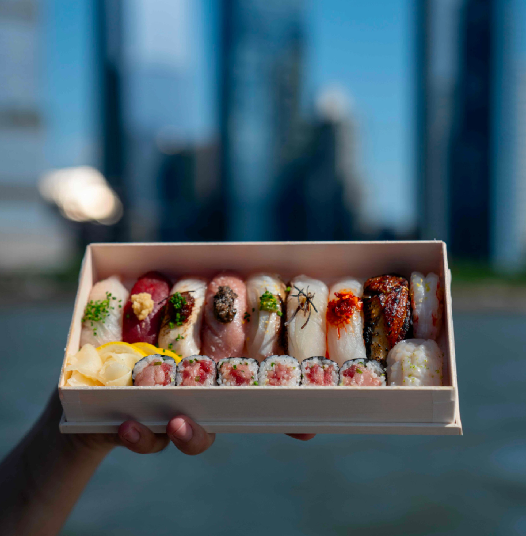 Beautiful sushi box presentation with blurred NYC skyline in the background