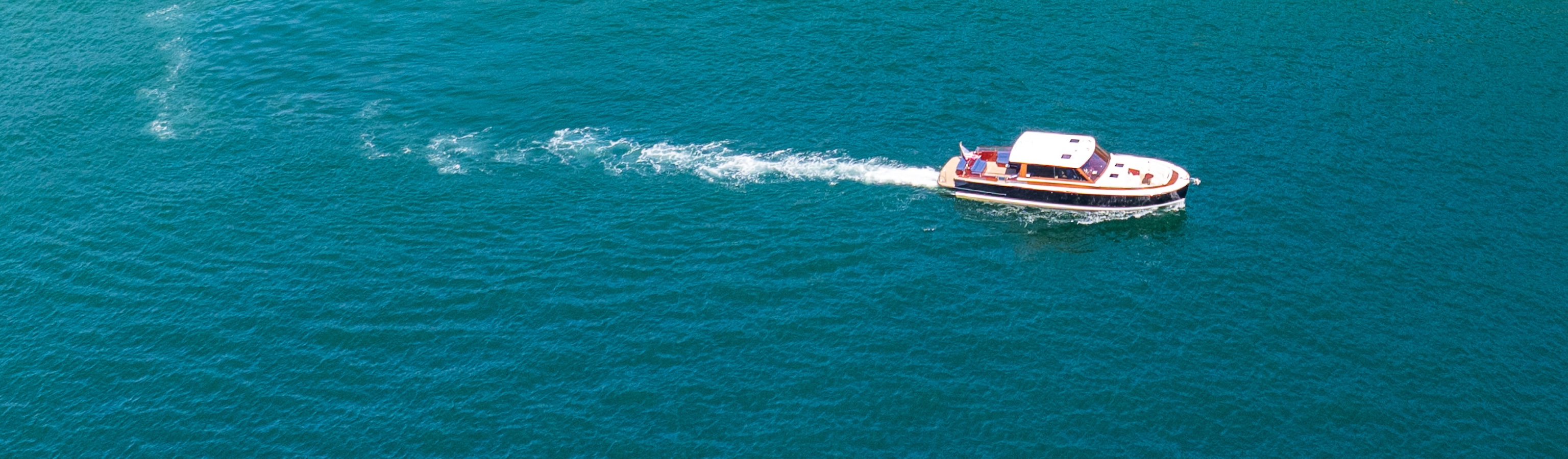 Aerial shot of a daychaser coasting on beautiful aqua waters with a tight wake being left behind.